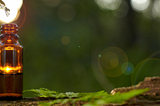 brown bottle with dropper above and drop of liquid, nature background