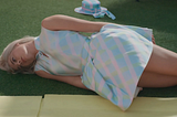 image from the Barbie movie where barbie (margot robbie) is lying on the ground looking hopeless