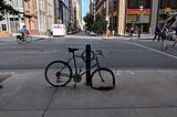 A bicycle with a flat tire tied to a pole.