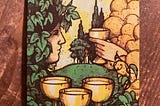 Tarot card, 4 of Cups, three cups in the foreground and someone on one side looking at a hand coming out of nowhere holding out another cup