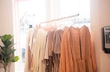 Dresses on a rack in a sunny room.