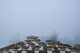 a set of short square columns on a hillside in the fog