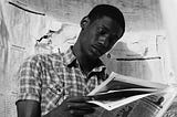 young Black person reading a newspaper