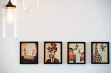 Four framed photos of illustrated giraffes on a white wall