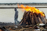 A person cremating a dead body at the shore of Ganges