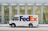 FedEx truck in front of a building with a Christmas tree inside