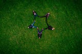 People lying on grass making a star shape with their bodies
