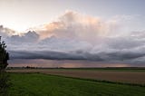 Panoramic photo of approaching storm clouds over farm fields.