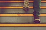 Person walking up a set of stairs to simulate climbing toward an accomplishment.