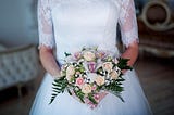 a bride in a white dress holding a bouquet of pink and white flowers
