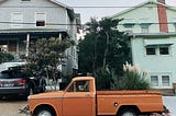 color photo of two houses with an older orange pickup truck parked out front