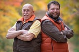 Dr. Jan Pol and Charles Pol stand back to back in vests in a field