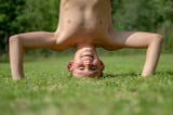 boy stands on his head in grass
