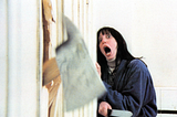 Shelley Duvall in the Shining as Wendy is terrified as an axe comes through the door. The Shining, Stephen King, Anne Hall, Kubrick, haunted hotel, Overlook, horror film, score, film, cinema, history, World Cup, soccer, Taylor and Justin, wedding, wedding dress, 250, where is, who is Shelley Duvall?