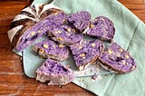 A sliced sourdough loaf that shows a purple hue from the ube and cheese bits