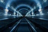 Track-level view of a subway tunnel perspective receding into the distance, with perimeter lights along the path