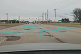 Screenshot of potholes detected by a camera installed on a moving vehicles. The potholes are marked with rectangular regions with detection confidence.