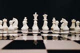 Black and white checkered chess board with only white pieces visible on it