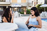 Two women having a business meeting and conversation outdoors at a table.