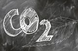 CO2 written on a blackboard with a leaf