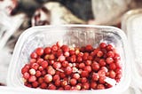 Frozen cranberries in an open plastic container.