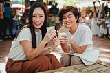 Pretty Asian women with takeaway coffees sitting in outdoor cafe