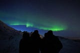 The Northern Lights with the shadow of four friends in front of it.
