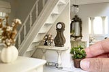 Hand carefully placing furniture in a dollhouse