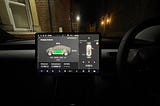 Photo of the Model 3 infotainment system at night with a house behind it