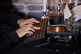 Color photo of a man typing on an older typewriter.