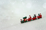 A toy train driving in snowy landscape.