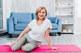 Portrait of a beautiful happy woman sitting on pink yoga mat