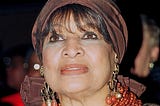 Civil rights activist Delores Tucker is pictured at a 1996 Washington D.C. Black caucus event. Tucker is wearing a brown head scarf, red lipstick and gold and red dangling earrings.