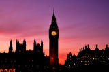 Pink sunset sky behind Big Ben clock in London, England.