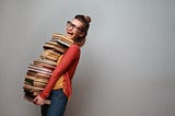 Happy woman carrying a giant stack of books.