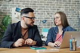 A guy and a gal having a discussion in the office.