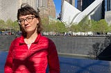 Photo of the author in a red jacket, standing in front of the 9/11 Memorial