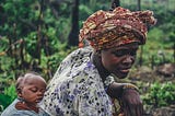 African woman working on a farm while carrying a baby on her back