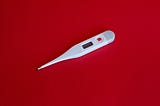 Thermometer on red background. Photo by Markus Spiske.