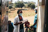 A masked healthcare worker is going door-to-door to deliver healthcare services in Mozambique.