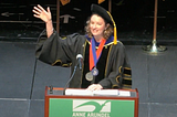 Dr. Hill waves at the crowd from a podium that says Anne Arundel Community College.