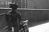 Ather sitting on a wheelchair facing the Philly skyline. The photo is taken from behind.