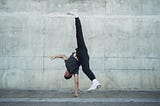 Man performing a handstand in a challenging breakdancing in the street.
