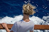 Man with headphones looking into the waves during a windy day