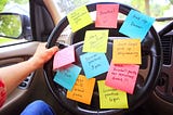 woman holding car steering wheel that is covered in post it notes