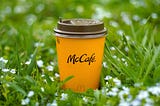 Picture of a McDonalds coffee cup sitting in a grassy field