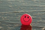 Happy face beach ball floating in water