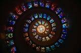 Stained glass domed ceiling with spiraling windows and a bright central window