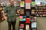 Martin standing beside a bookshelf. He is wearing a green top and black bottoms. Credit: M.Tran