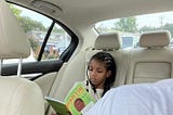Photo of the author’s daughter reading a Martin Luther King Jr. book in the car.